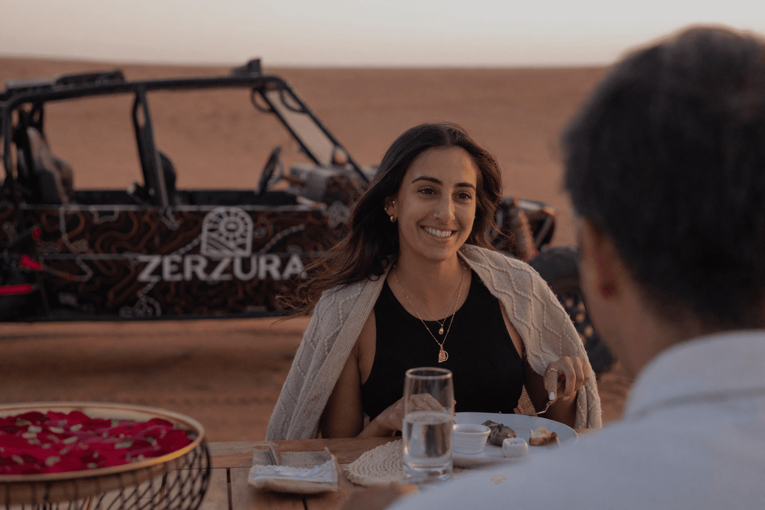 Couple enjoying luxury desert dining experience near dune buggy at Zerzura