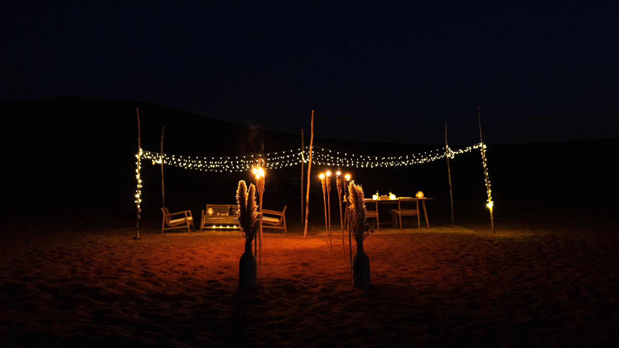 Private dinner setup in Mleiha desert with lantern lights at sunset near Dubai
