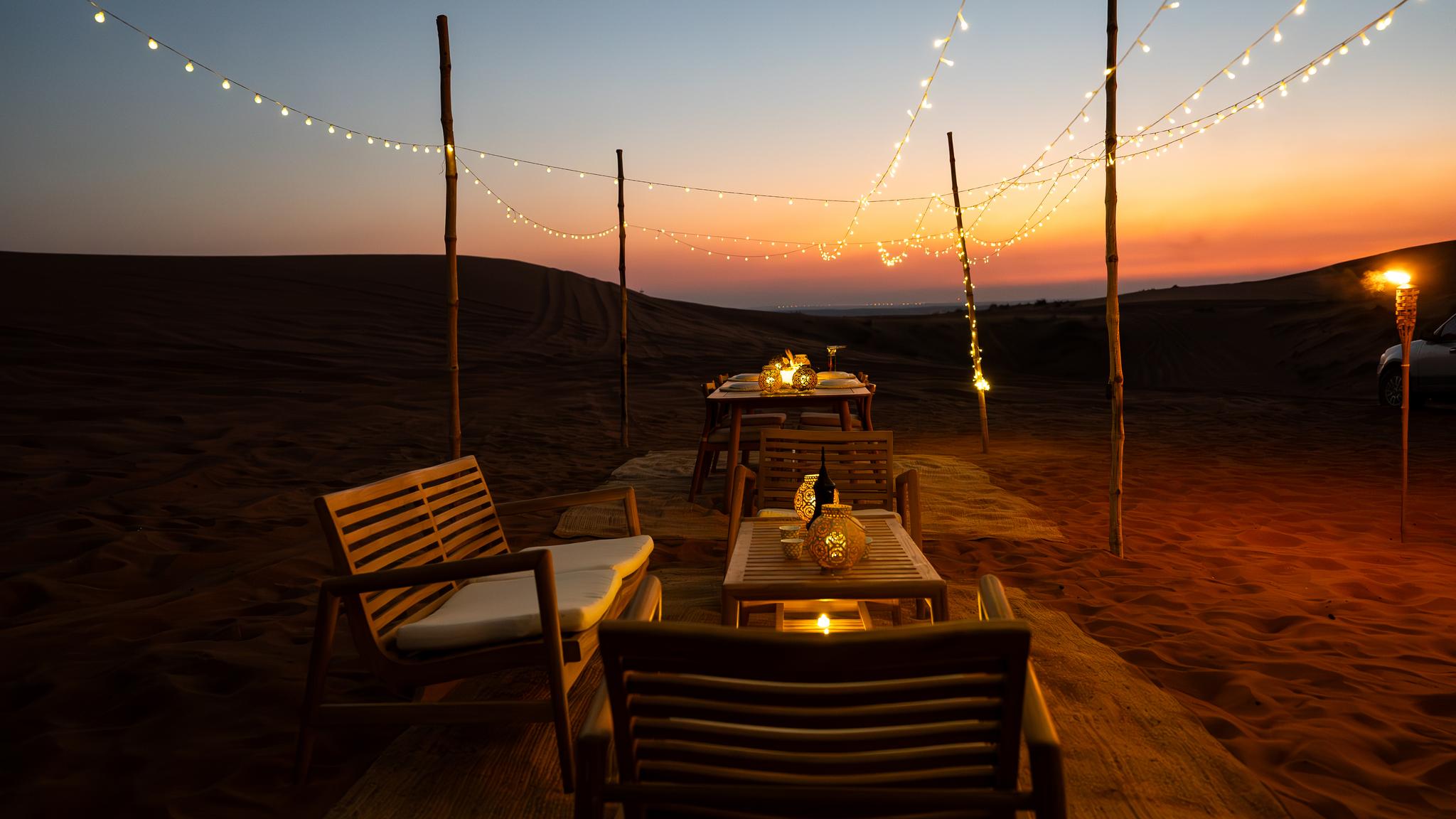 Elegant private desert dining setup in the dunes at sunset in Mleiha