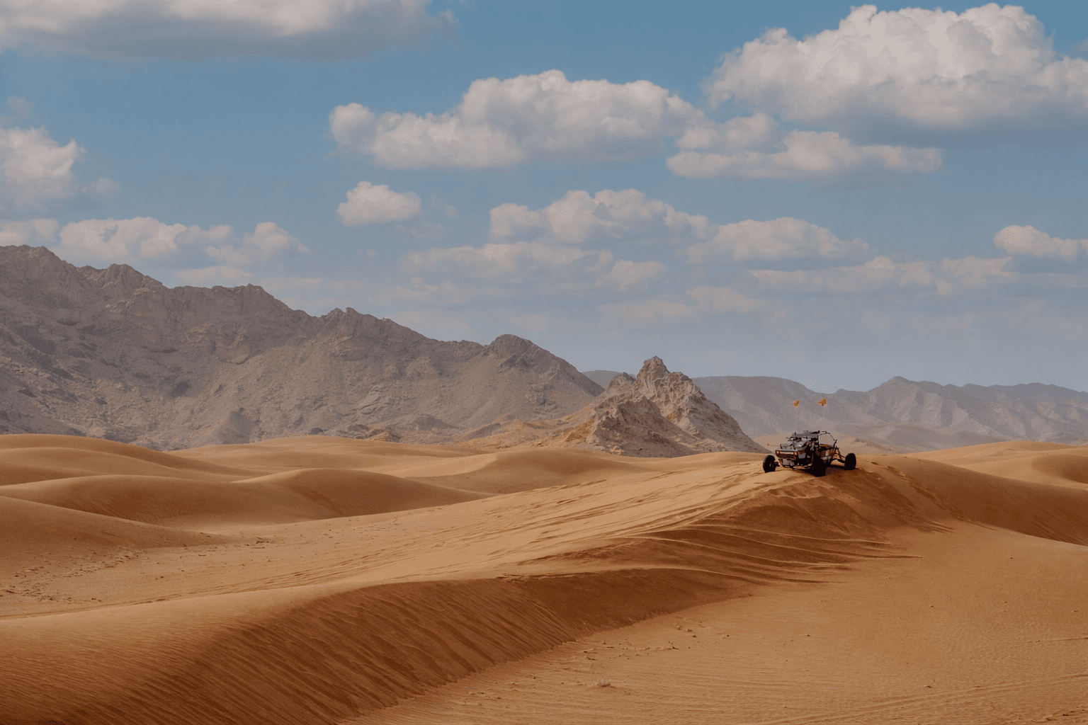 Wide desert landscape with Zerzura dune buggy on Mleiha sand dunes